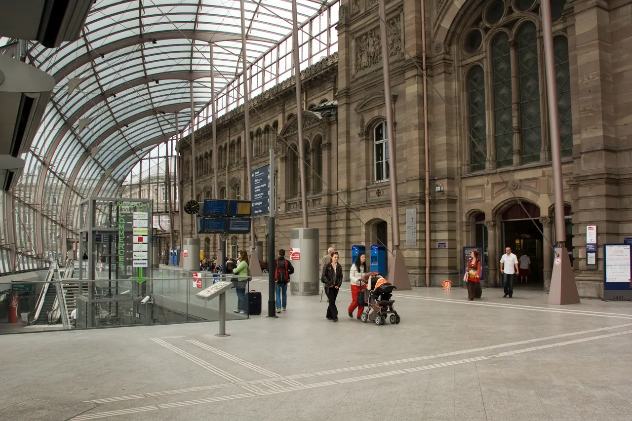 Travellers with suitcases under the glass canopy of Strasbourg station